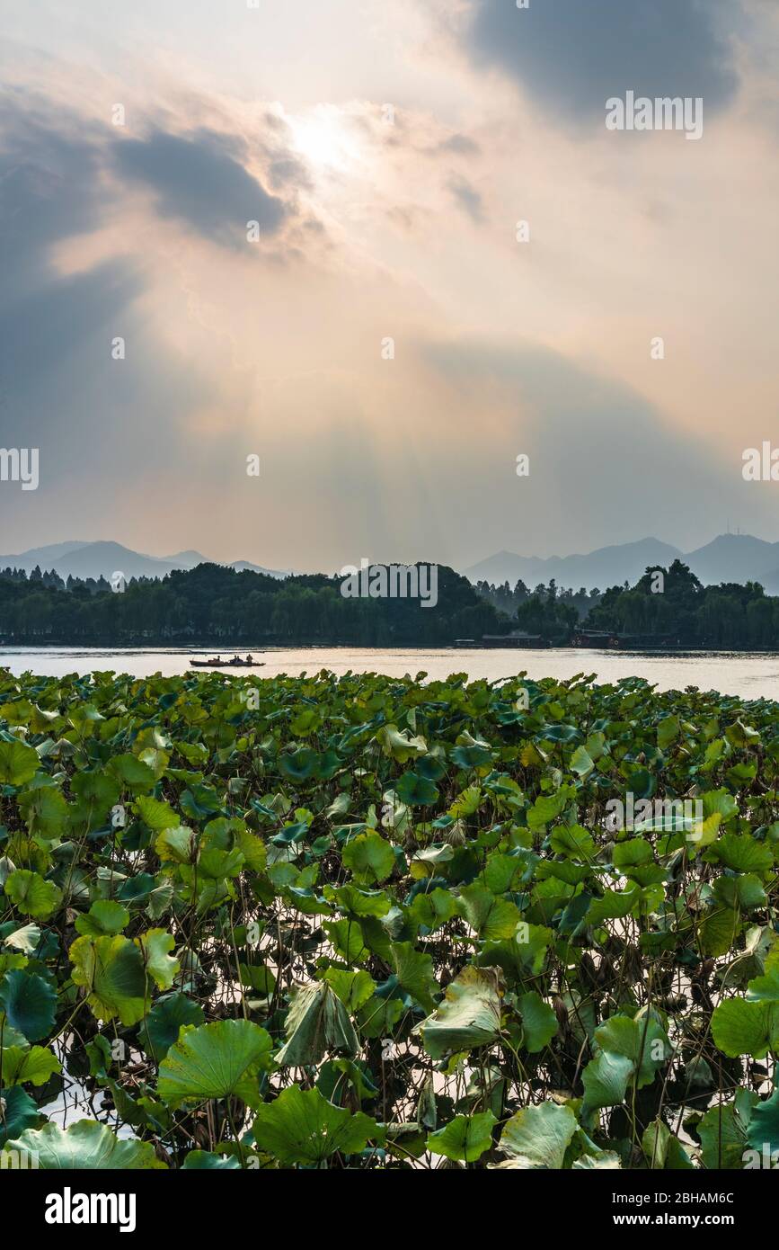 Asia, Repubblica popolare Cinese, Cina Orientale, Provincia di Zhejiang, Hangzhou, XÄ«zÇ Hú, il Sole si rompe attraverso le nuvole sul Lago Ovest Foto Stock