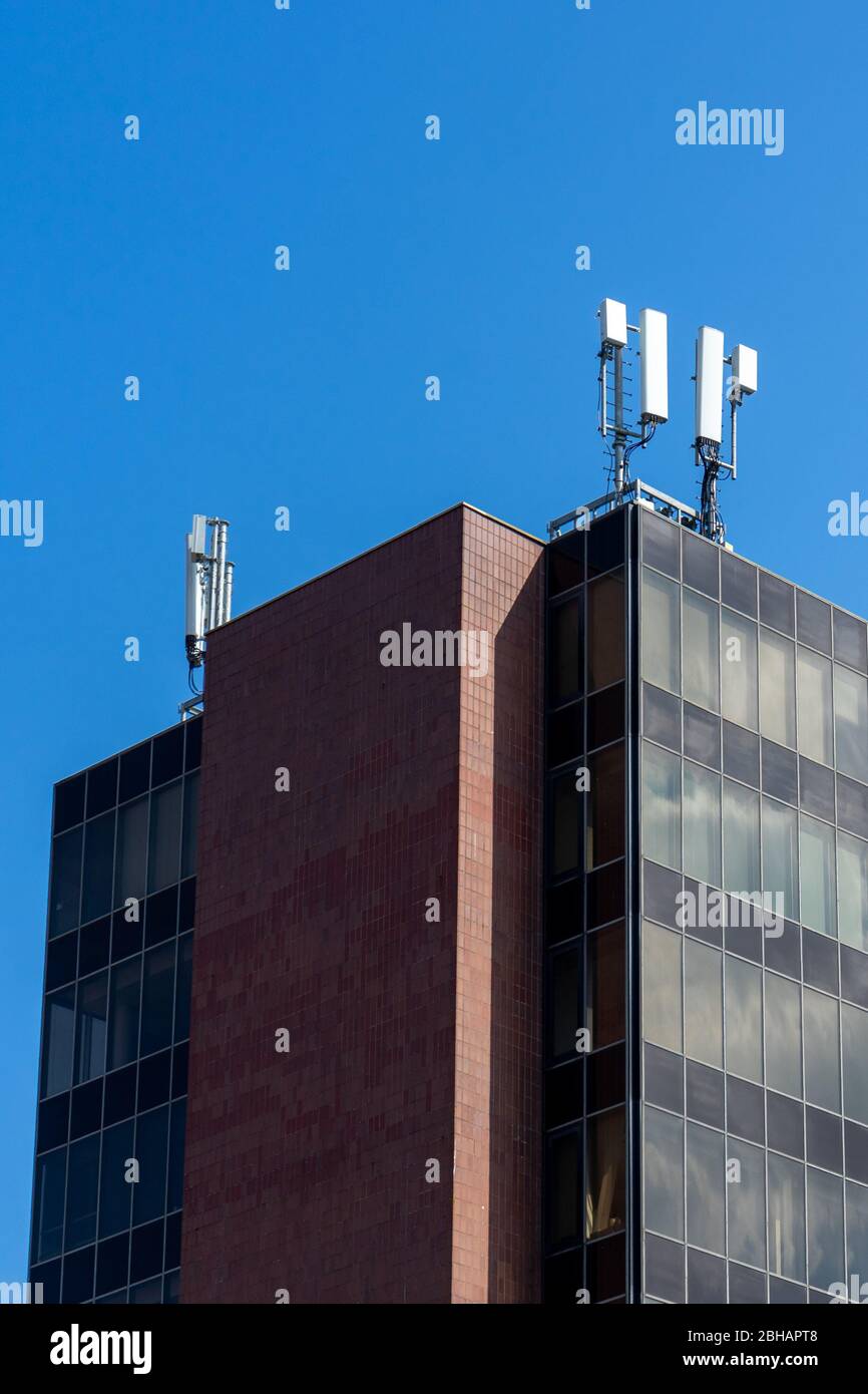 Un moderno blocco da ufficio con antenne 5G sulla parte superiore di per la ricezione di telefoni cellulari o cellulari Foto Stock