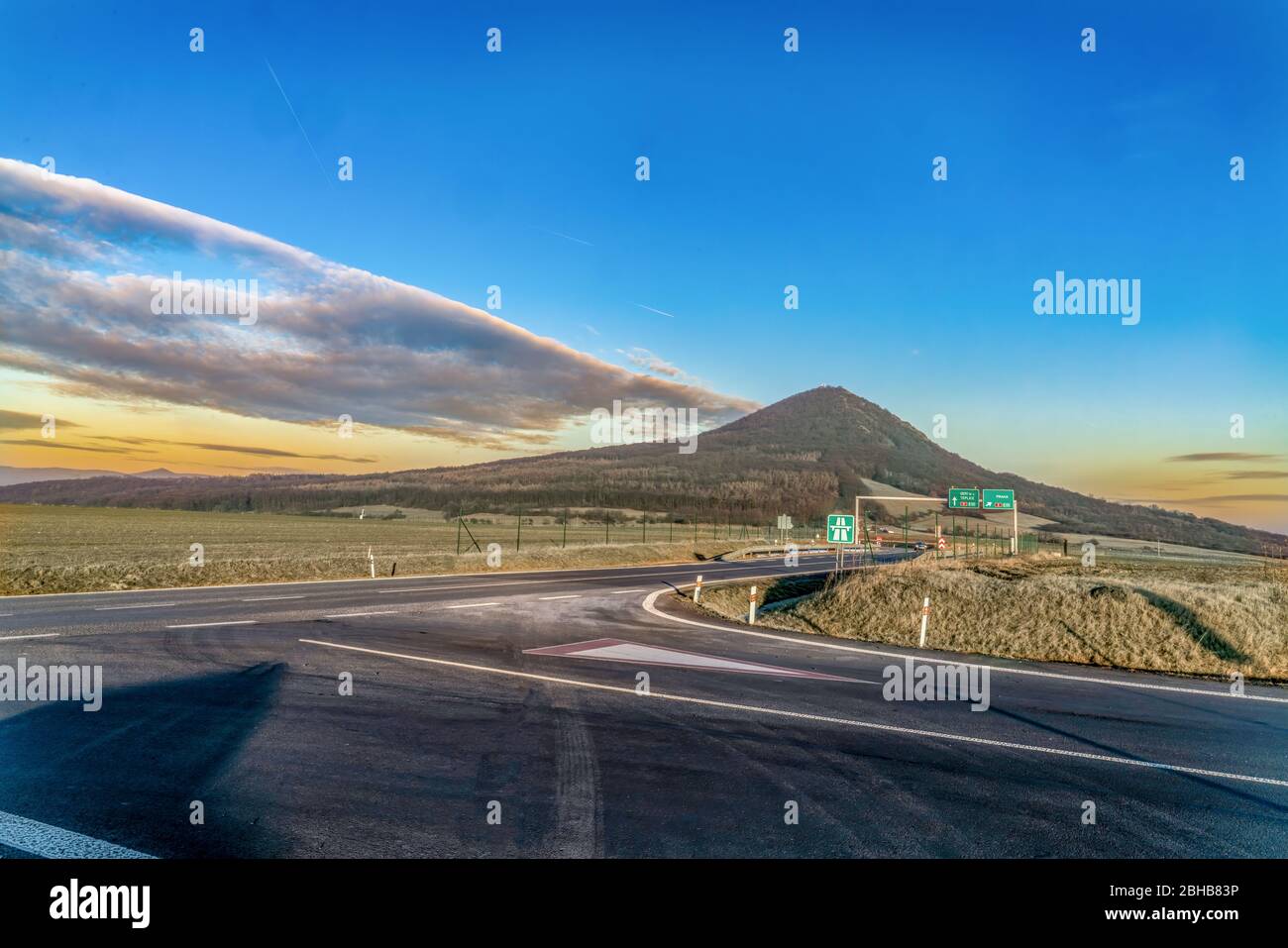 Vista panoramica di un incrocio sulla strada su montagne e cielo colorato Foto Stock
