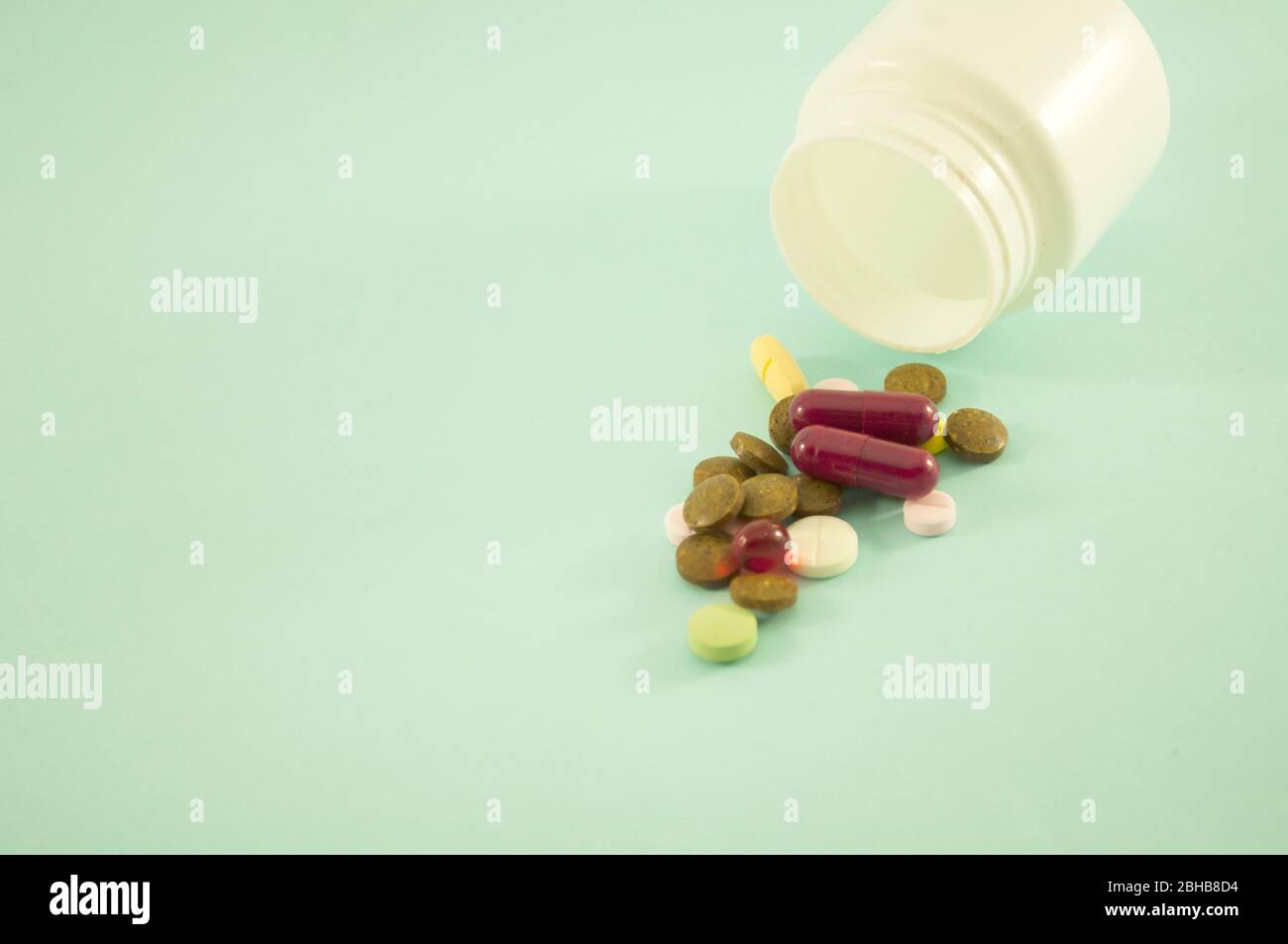 Mescolare le pillole e la bottiglia per le pillole su uno sfondo blu. Pillole sparse con vasi bianchi su sfondo verde. Spazio di copia per il testo Foto Stock