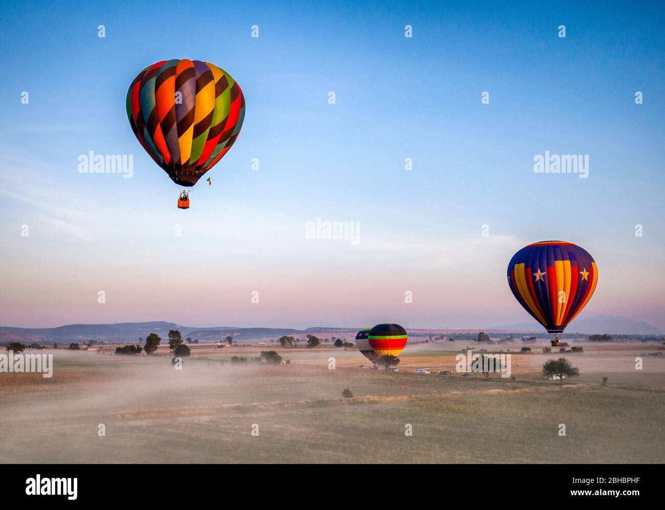 I palloncini ad aria calda all'alba si innalzano su campi infurianti vicino a Tequisquiapan, Queretaro, Messico. Foto Stock