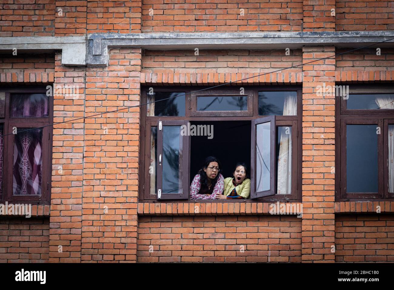 Lalitpur, Nepal. 24 Aprile 2020. Madre e sua figlia che guardano fuori attraverso una finestra di legno durante il covid 19 confino.IT è stato un mese dal blocco. Tutti rimangono al chiuso, tranne quando escono per comprare gli essenziali. Per coloro che sono confinati nelle loro case, la vista del mondo esterno è solo attraverso la finestra. Credit: SOPA Images Limited/Alamy Live News Foto Stock