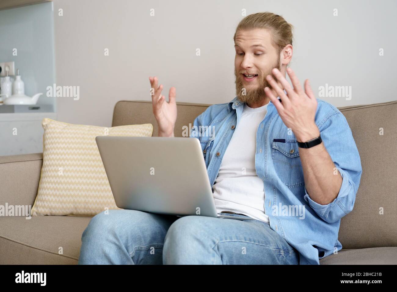 Le videochiamate dei giovani sul laptop sono seduti sul divano mentre lavorano da casa. Foto Stock