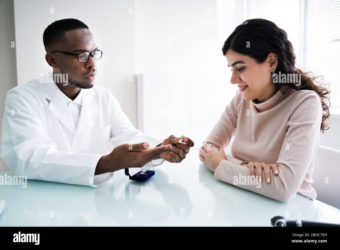Primo piano del medico che mostra il supporto all'udito per il paziente Foto Stock