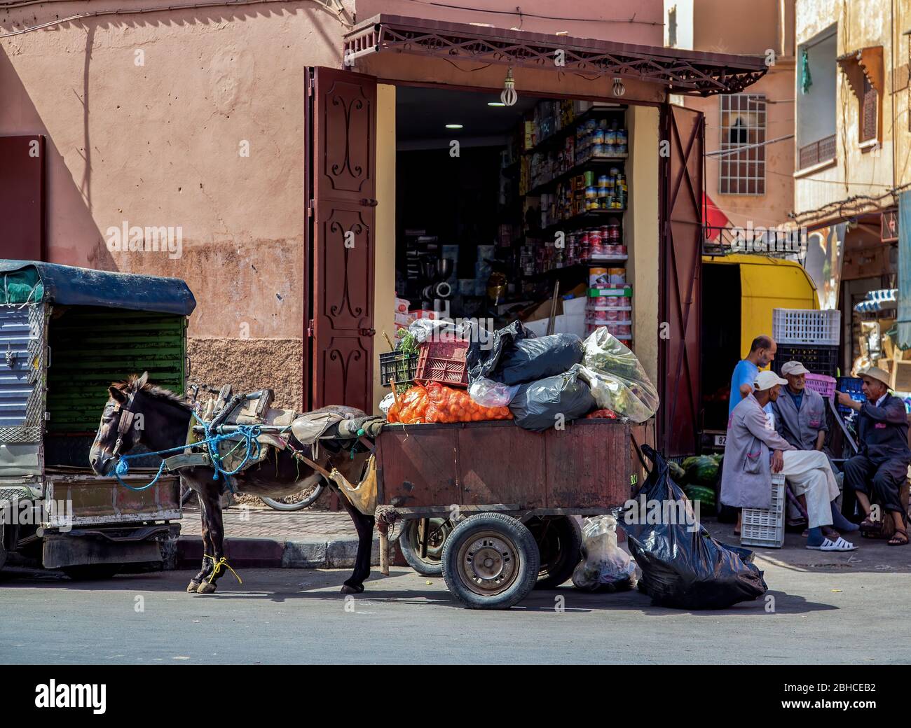 Tipico negozio di cibo Medina di Marrakech. Carrozza asino in primo piano, chiacchierando con la gente del posto sullo sfondo.Marocco. Foto Stock