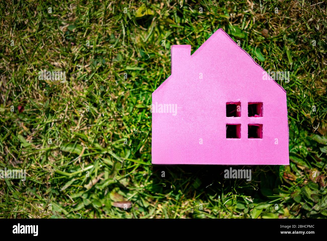 Un palo rosa si nota casa su un giardino di erba sfondo . Concetto di mercato immobiliare Foto Stock