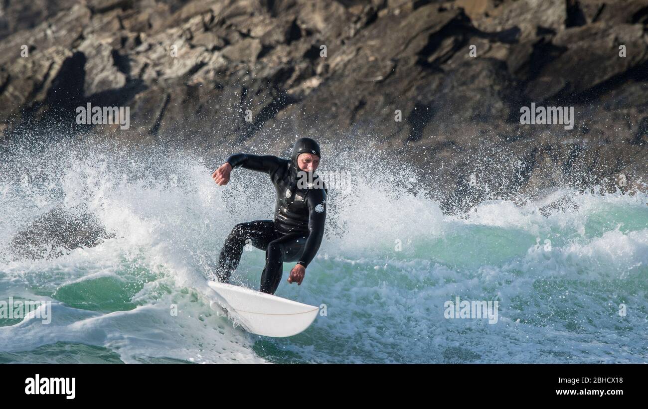 Un'immagine panoramica di un surfista maschile maturo che cavalca un'onda a Fistral a Newquay in Cornovaglia. Foto Stock