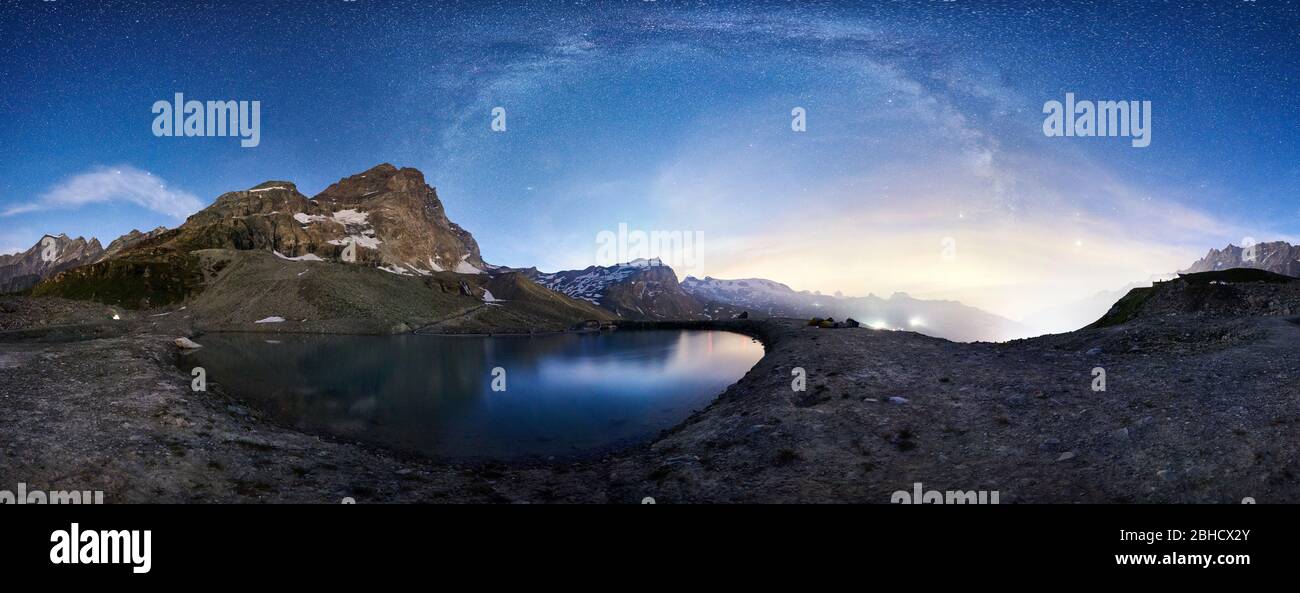 Vista panoramica del picco piramidale Cervino che riflette sul foglio di acqua cristallina sotto il cielo notturno con le stelle. Bellissima strada Lattea su montagne rocciose e piccolo lago. Concetto di natura, notte. Foto Stock