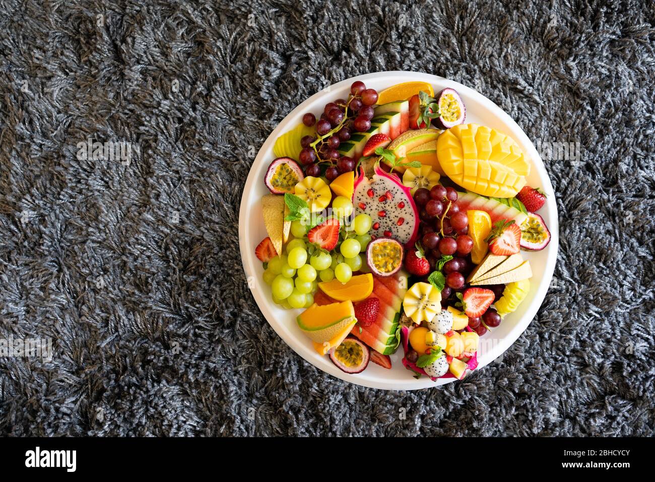 vista dall'alto ampio vassoio di frutta fresca tropicale a fette su sfondo grigio Foto Stock