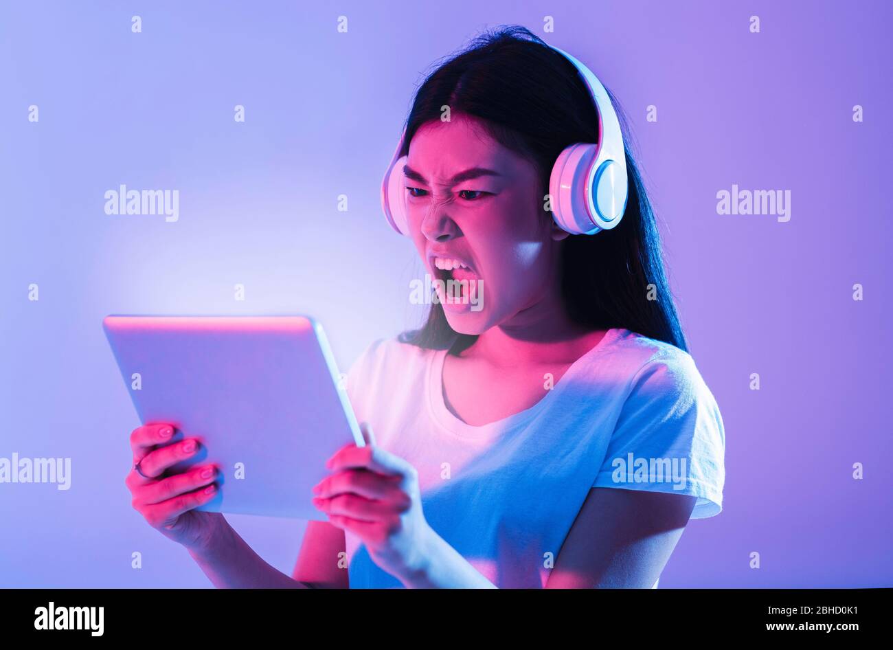 Donna asiatica che urla con tablet e cuffie Foto Stock