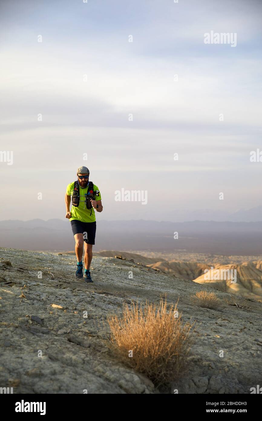 Runner atleta con zaino in esecuzione sul sentiero selvaggio a monti rossi nel deserto Foto Stock