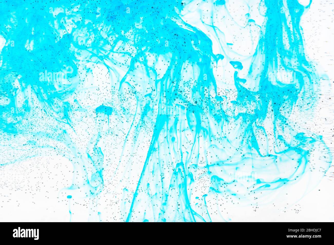 bolle d'aria sulla superficie di vetro della bottiglia piatta e l'inchiostro acquamarina fluiscono nell'acqua sullo sfondo Foto Stock
