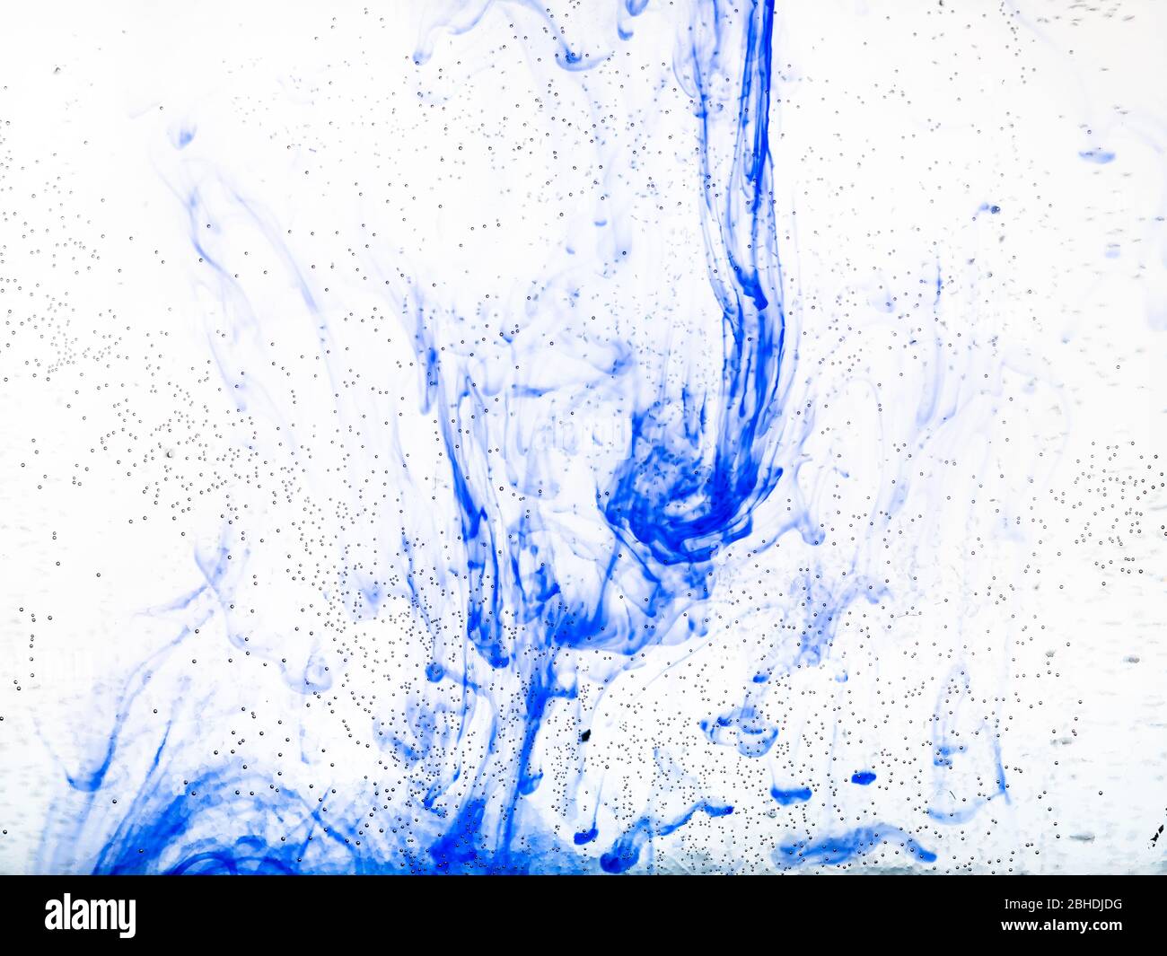 bolle d'aria sulla superficie di vetro della bottiglia piatta e inchiostro blu che si dissolve in acqua sullo sfondo Foto Stock