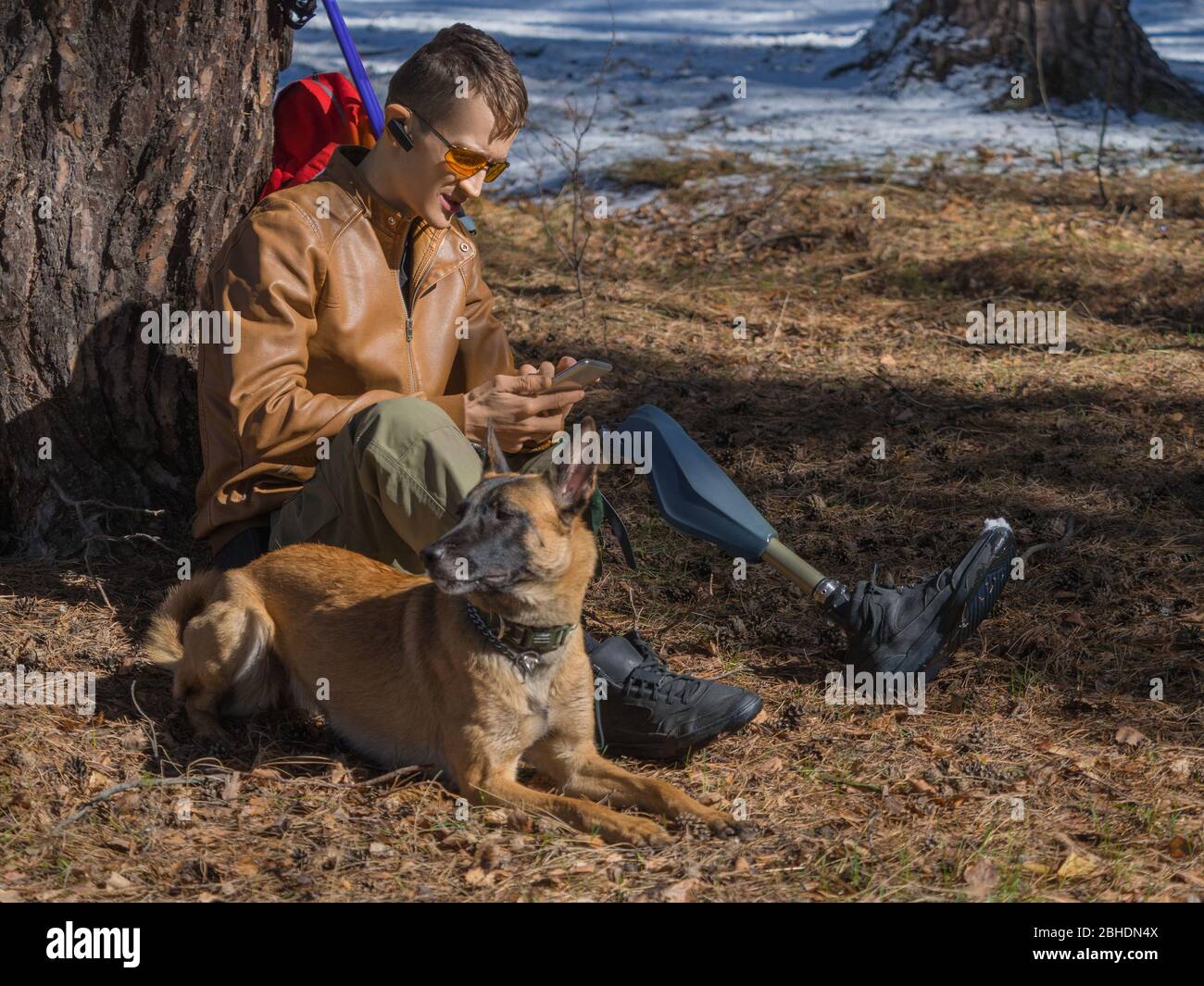 Foto ravvicinata di un uomo con protesi riposa dopo una lunga passeggiata con il suo migliore amico - un cane da un rifugio. Concetto di amicizia e sostegno Foto Stock