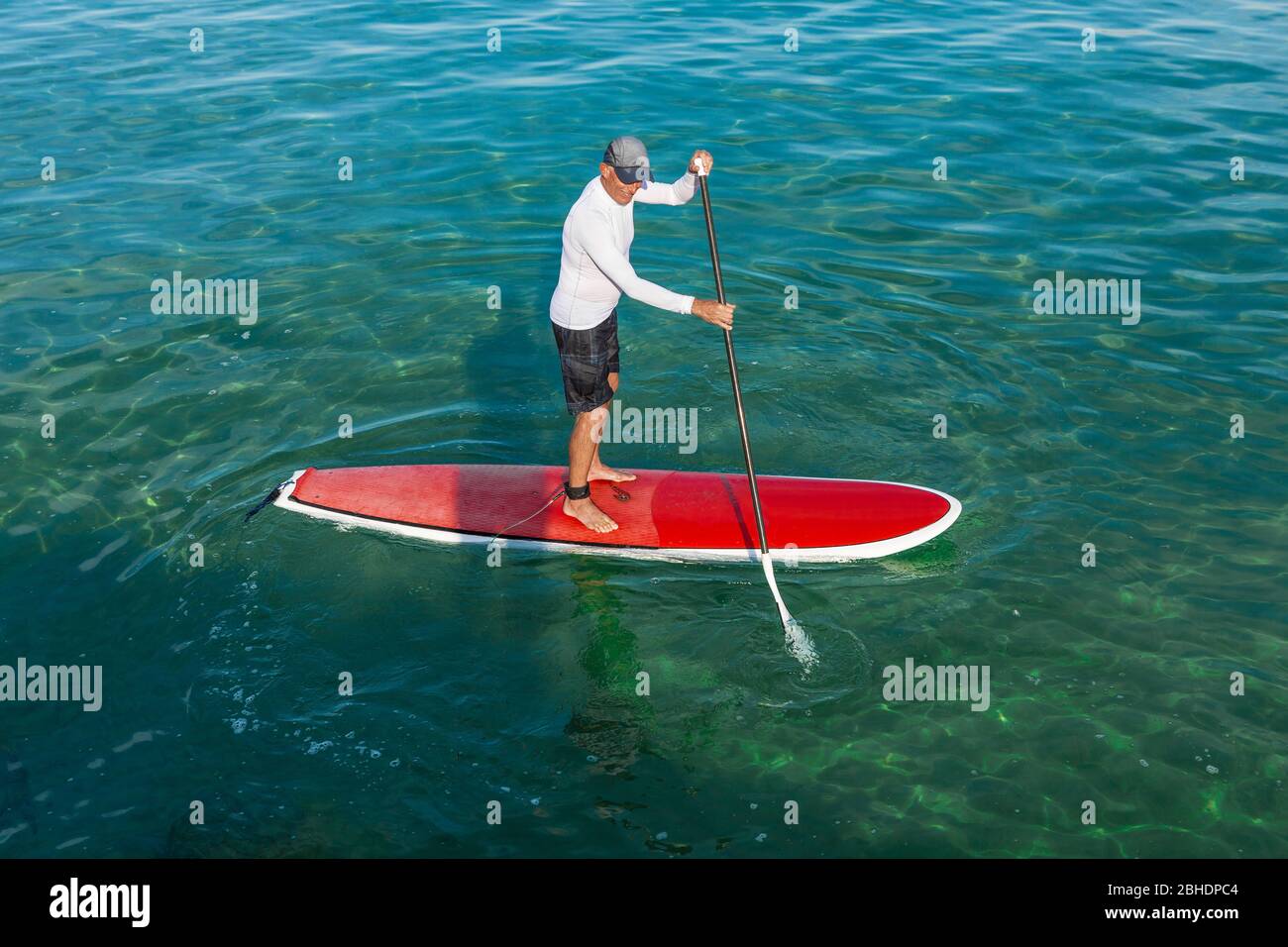 Un anziano uomo pratica paletta in una bella giornata di sole Foto Stock