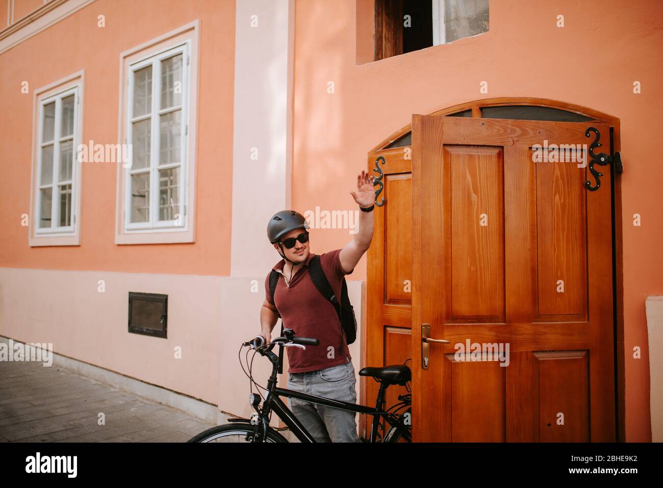 Bel giovane ciclista caucasica in piedi di fronte a casa e. onde Foto Stock