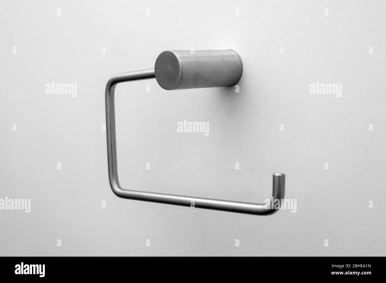 Un supporto per rotolo di carta igienica vuoto su una parete bianca Foto Stock