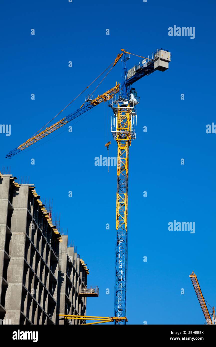 Costruzione di case in cemento. Telaio e gru. La costruzione di un alto edificio residenziale e di un parcheggio. Via. Foto Stock