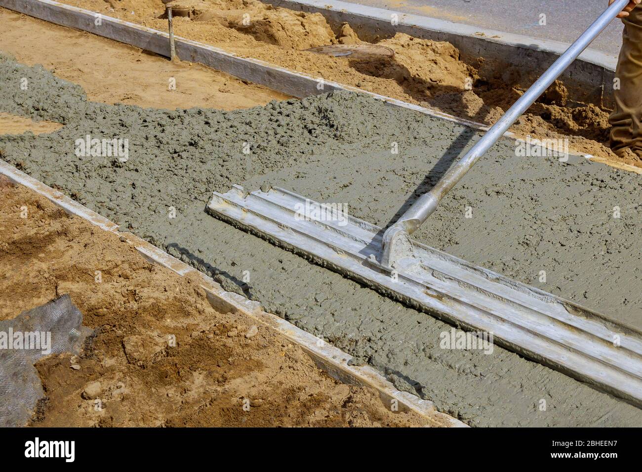 Rifinendo il marciapiede in calcestruzzo, l'operatore di costruzione  livella la pavimentazione in calcestruzzo all'esterno Foto stock - Alamy