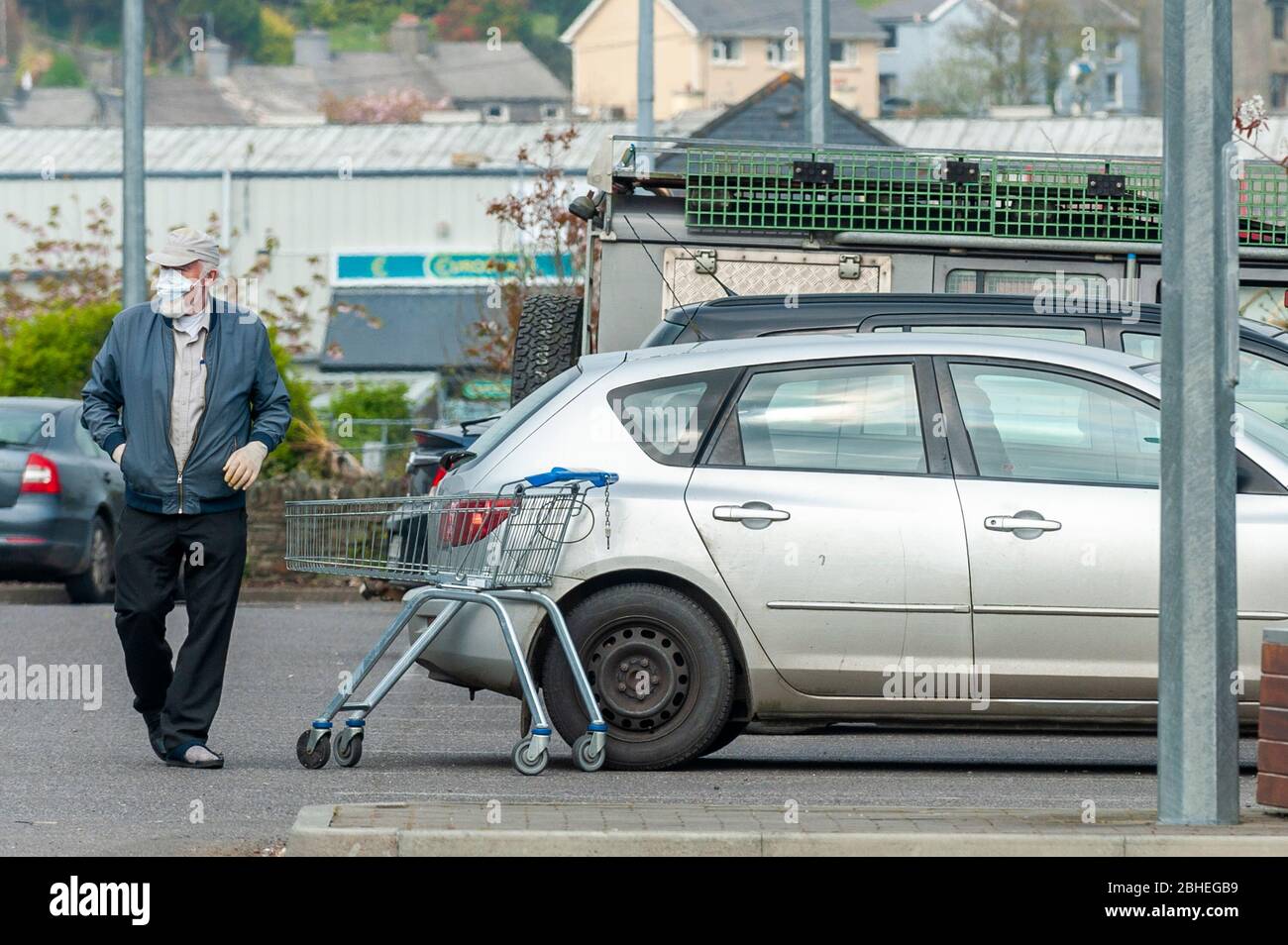 Skibbereen, West Cork, Irlanda. 25 Aprile 2020. Un uomo carica la sua auto con lo shopping a Lidl, Skibbereen, indossando una maschera protettiva e guanti per proteggersi contro Covid-19. Credit: AG News/Alamy Live News Foto Stock