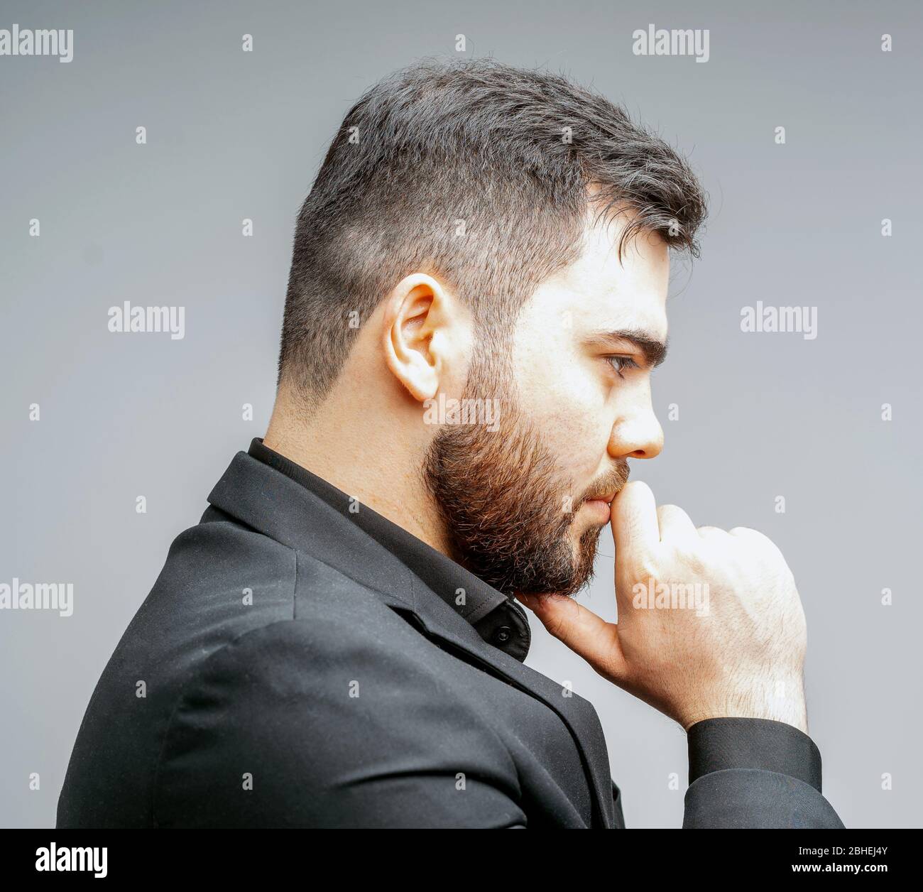 Giovane bell'uomo con barba e mano sul mento pensando alla domanda, espressione pensiva. Viso pensoso. Concetto di dubbio. Foto Stock