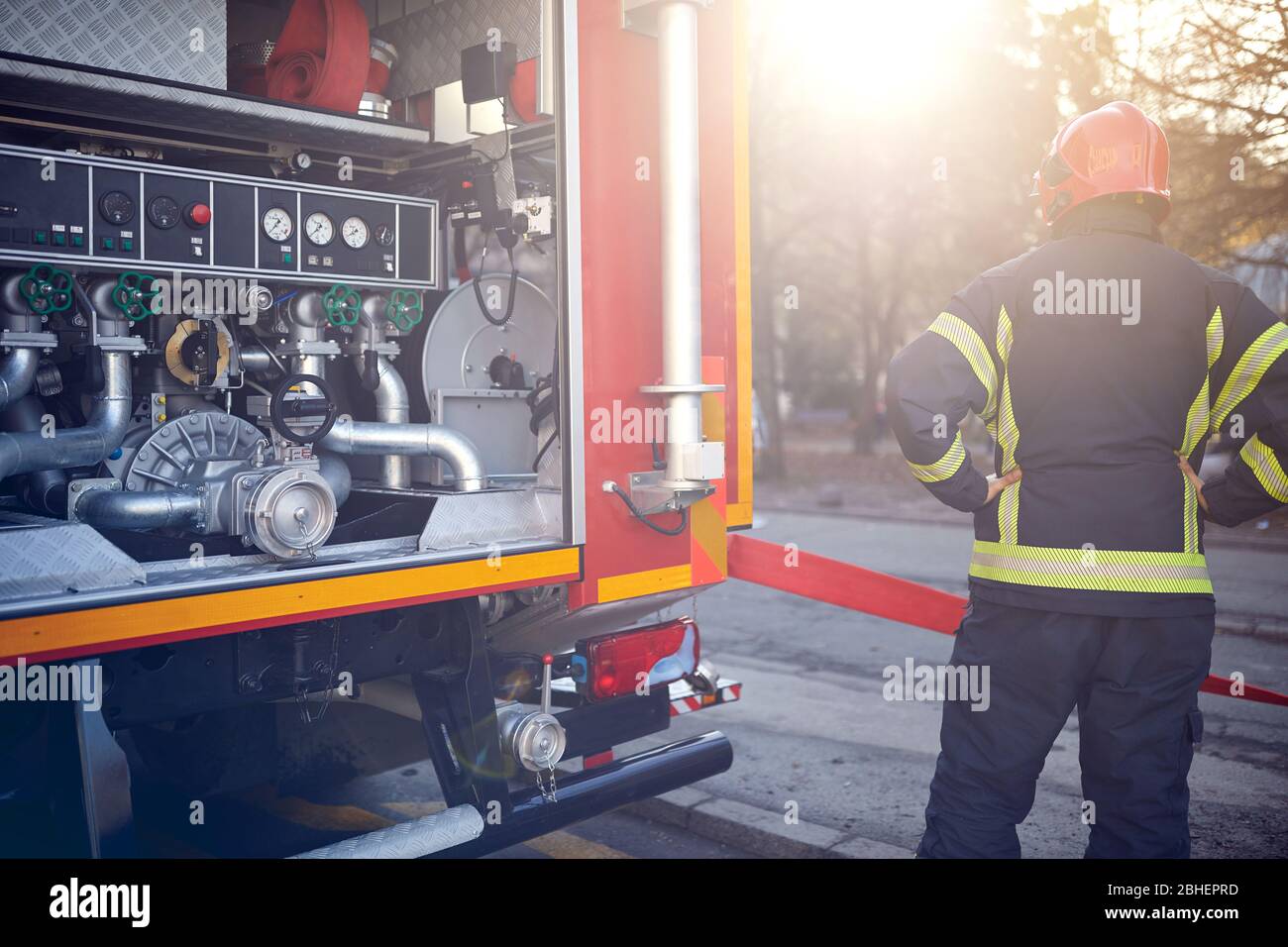Vigili del fuoco in azione in piedi vicino a un camion antincendio. Attacco, pericolo, fuoco. Foto Stock