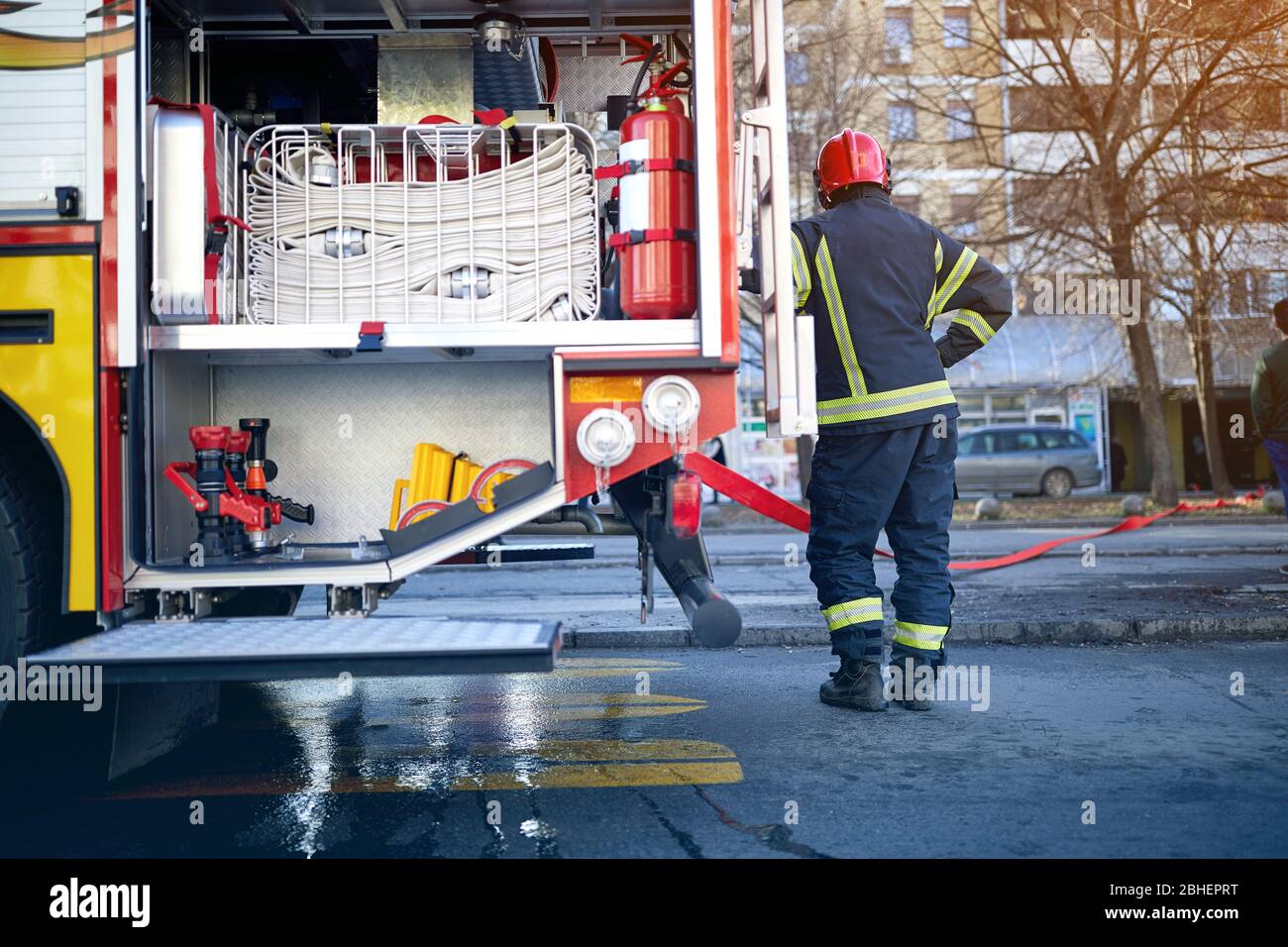 Uomo vigile del fuoco in piedi vicino al motore del fuoco e al lavoro.. First Responders – pompieri. Foto Stock