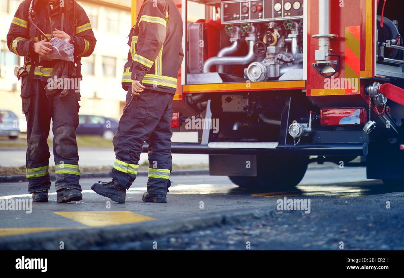 Camion antincendio professionale con attrezzature antincendio e pompieri in abbigliamento protettivo, caschi e maschera. Foto Stock