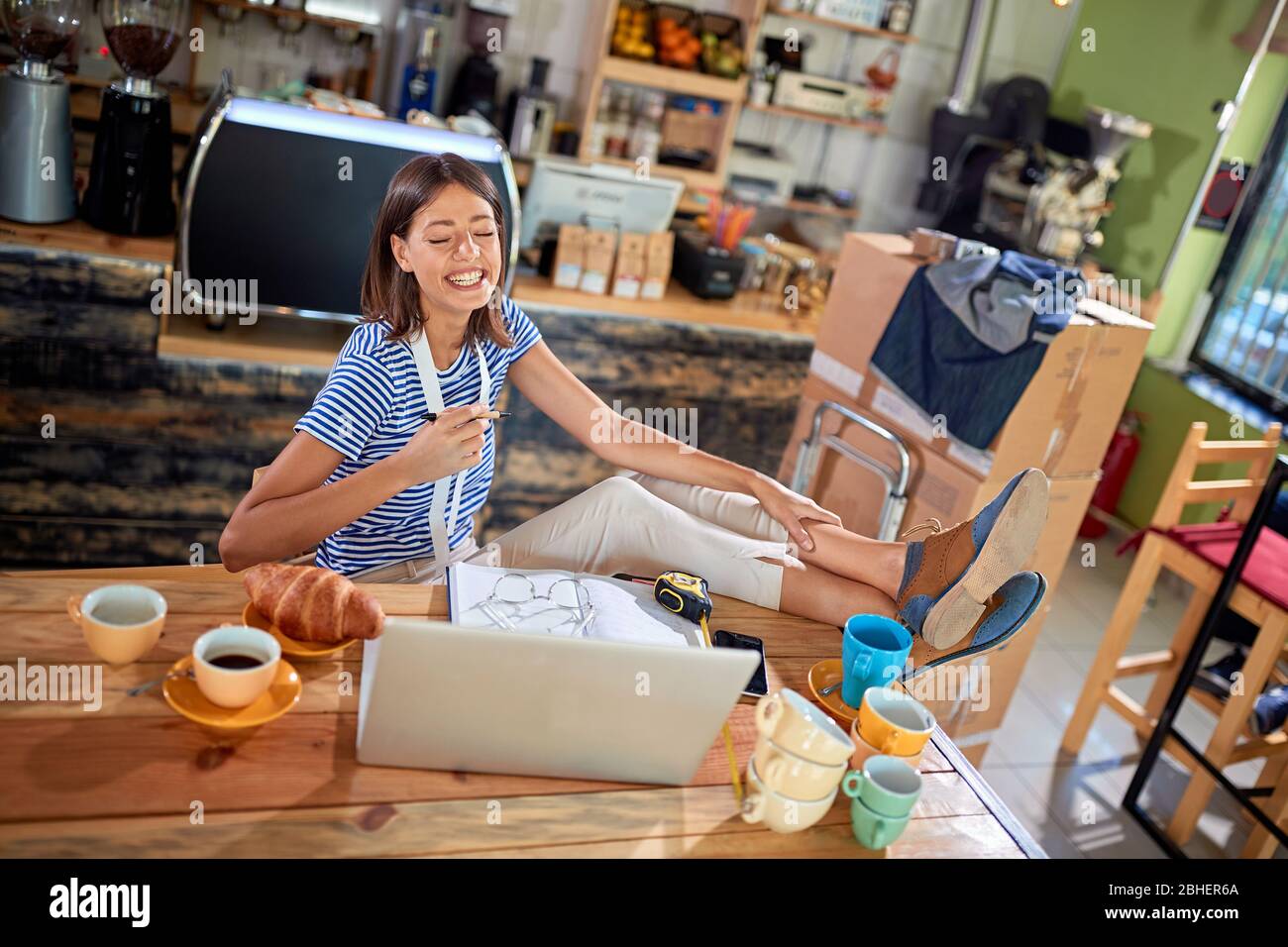 donna che guarda contenuti sul suo laptop, ridendo , con le gambe sul tavolo. casual, rilassato, pausa, pausa Foto Stock