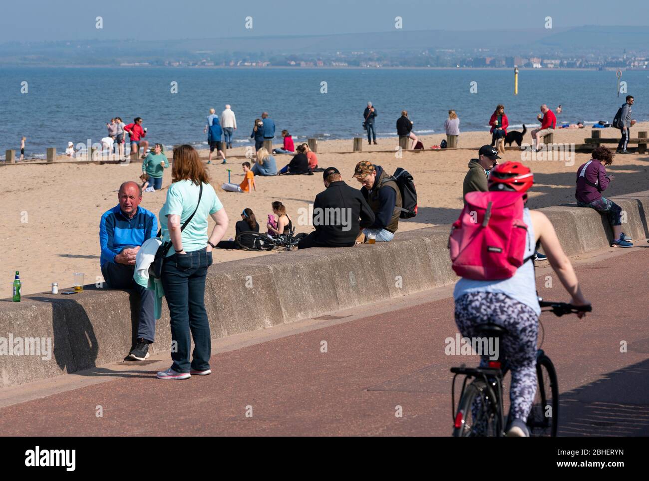 Portobello, Scozia, Regno Unito. 25 aprile 2020. Vista della gente all'aperto il sabato pomeriggio sulla spiaggia e sul lungomare di Portobello, Edimburgo. Il bel tempo ha portato più persone all'aperto a piedi e in bicicletta. La spiaggia sembra occupata con possibile un guasto nelle distanze sociali che accadono più tardi nel pomeriggio. Promenade e spiaggia sembrano occupati ma gruppi individuali di persone generalmente mantenendo le distanze sociali. Iain Masterton/Alamy Live News Foto Stock