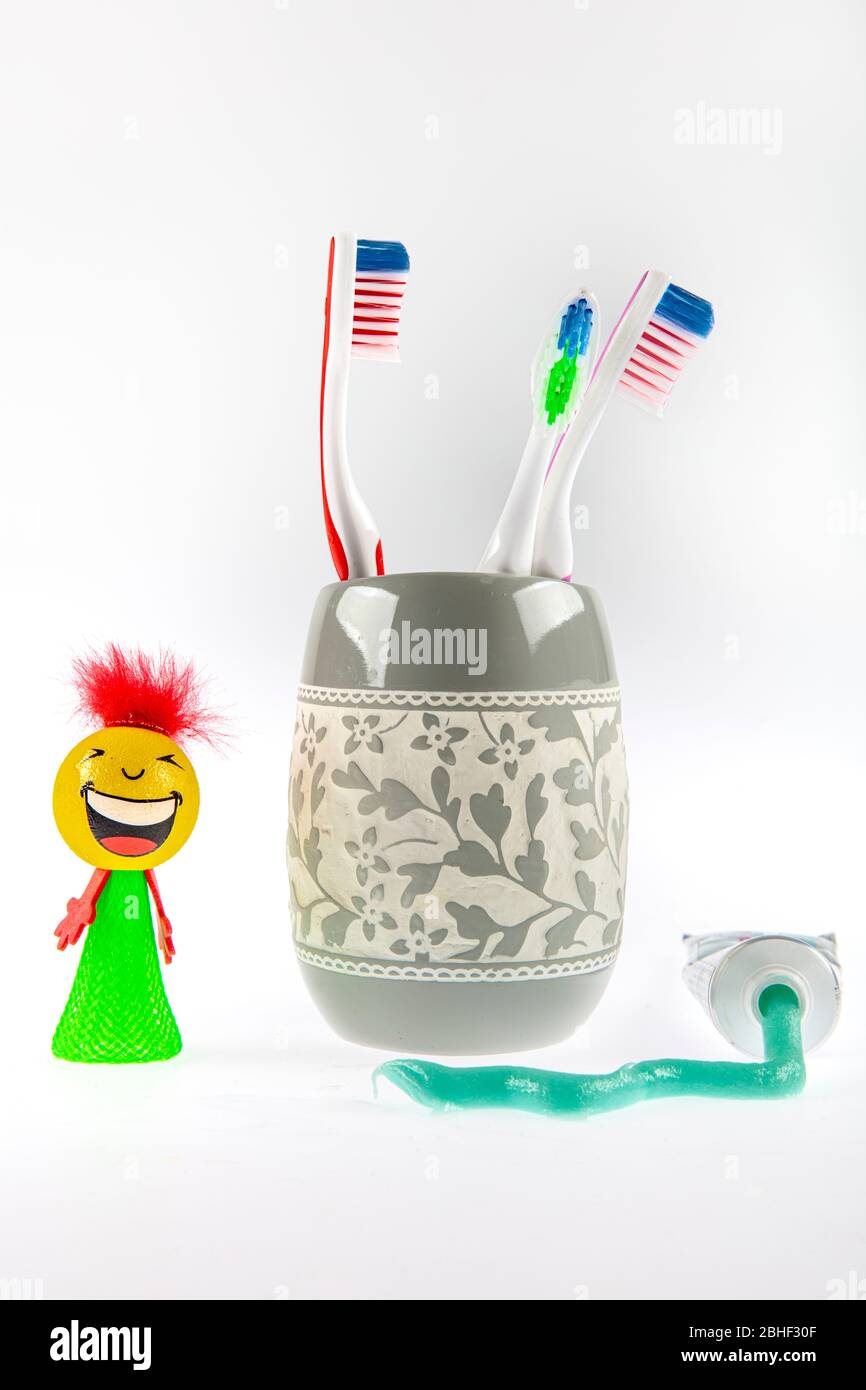 Dentifricio verde e spazzolini multicolore in un bicchiere speciale accanto a un tubo di dentifricio. Ancora vita. Foto Stock