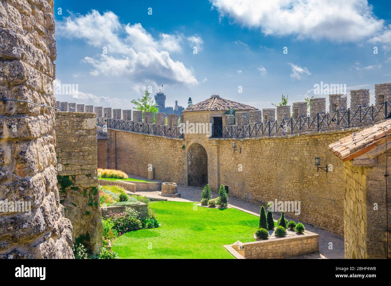 Repubblica San Marino, 18 settembre 2018: Mura fortilizio in mattoni di pietra con merli e cortile della prima Torre Guaita prima torre e seconda Torre la testa sulla roccia del Monte Titano con cielo blu Foto Stock
