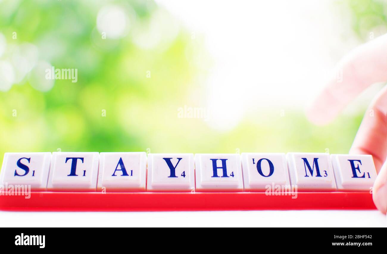 Coronavirus o COVID 19 concetto: Soggiorno a casa. Fare parole scrabble da lettere di mattonella. Quarantena, concetto di blocco Foto Stock