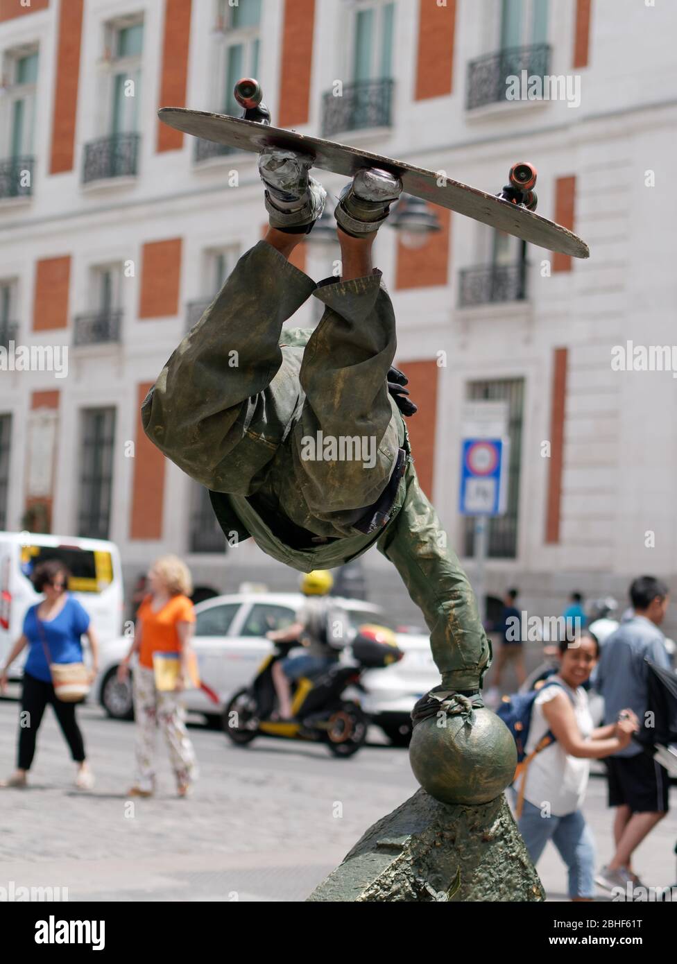 Artista di strada che recita una statua di bronzo di uno skateboarder che mostra il trucco dello skateboard per divertire i turisti a Puerta del Sol. Foto Stock