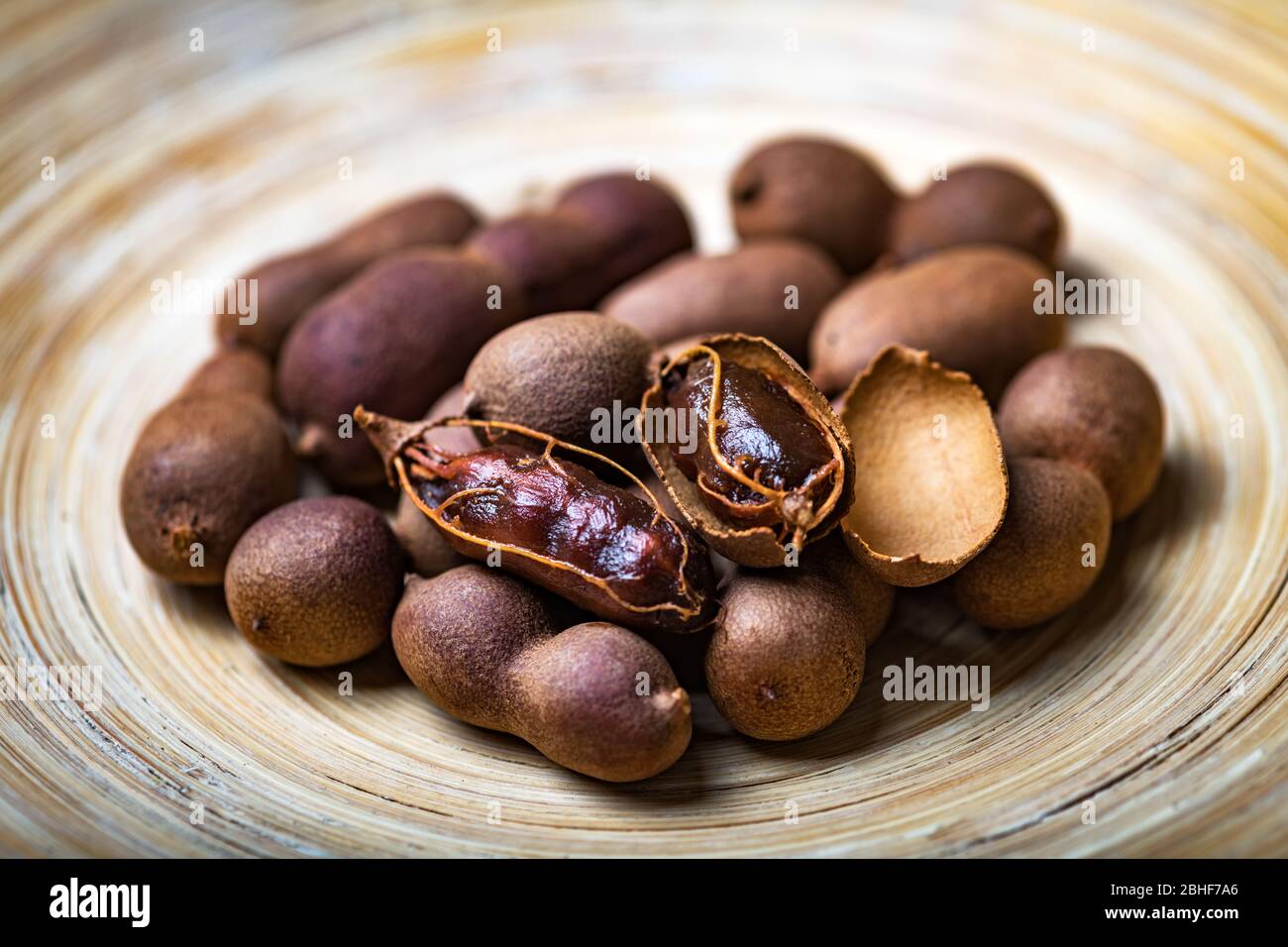 Frutta esotica e biologica essiccata tamarindo in ciotola di bambù primo piano. Studio macro Shoot Foto Stock