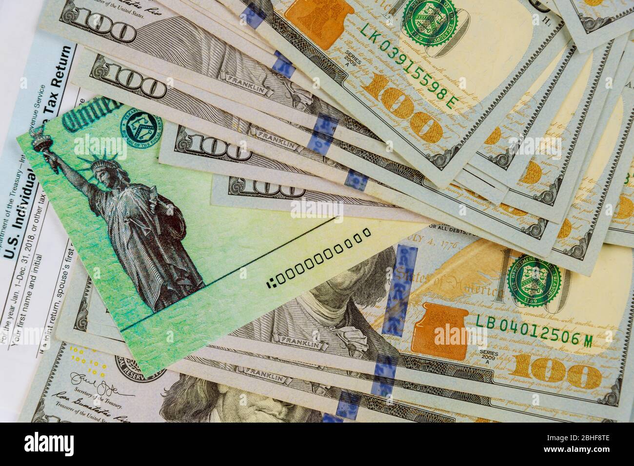 Assegno di rimborso closeup e valuta banconote in dollari USA sul modulo fiscale 1040 Foto Stock