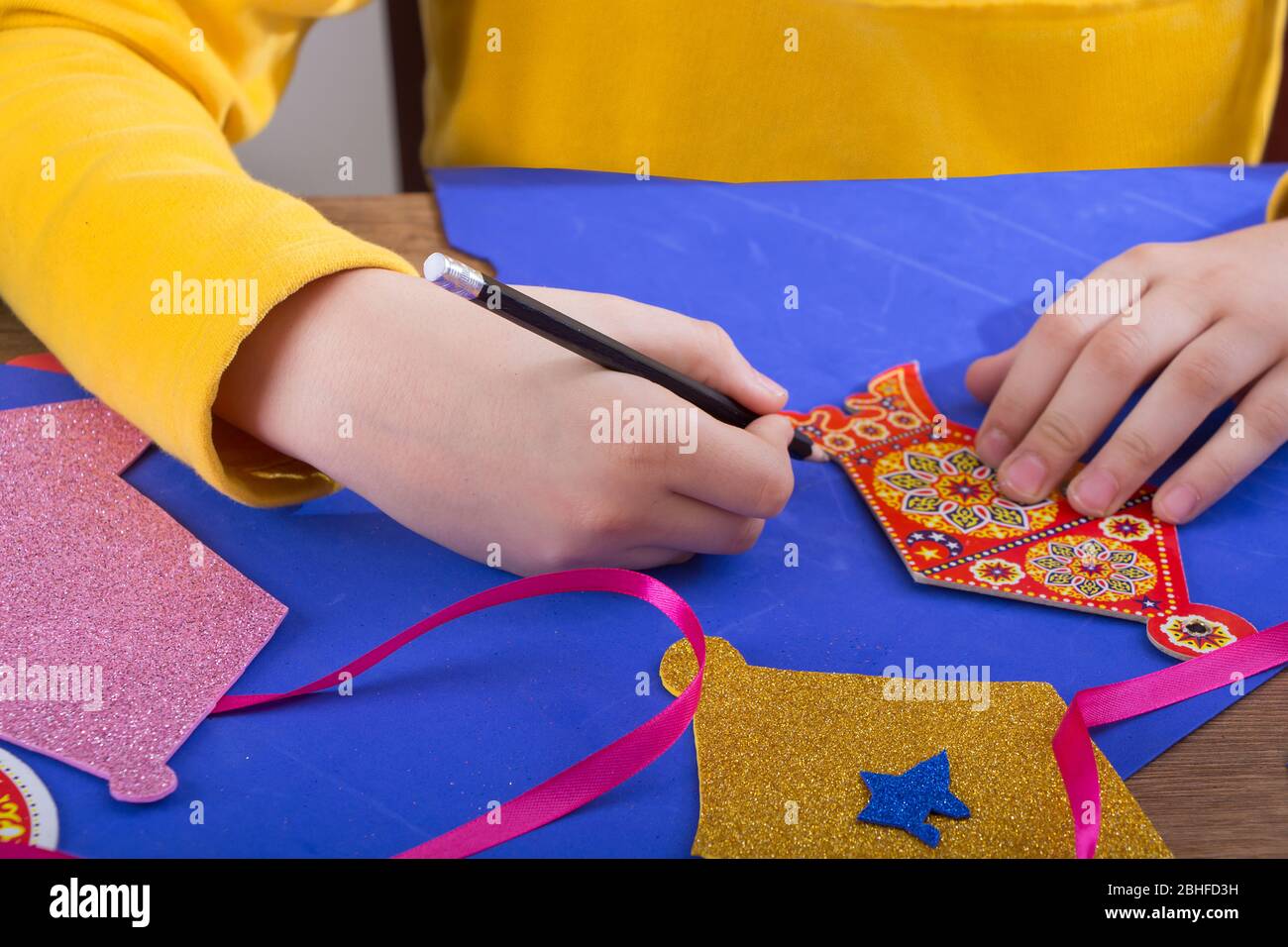 Primo piano delle mani dei bambini preparare la decorazione domestica di Ramadan usando carta colorata - diy Ramadan zeena e lanterna fatte a mano Foto Stock