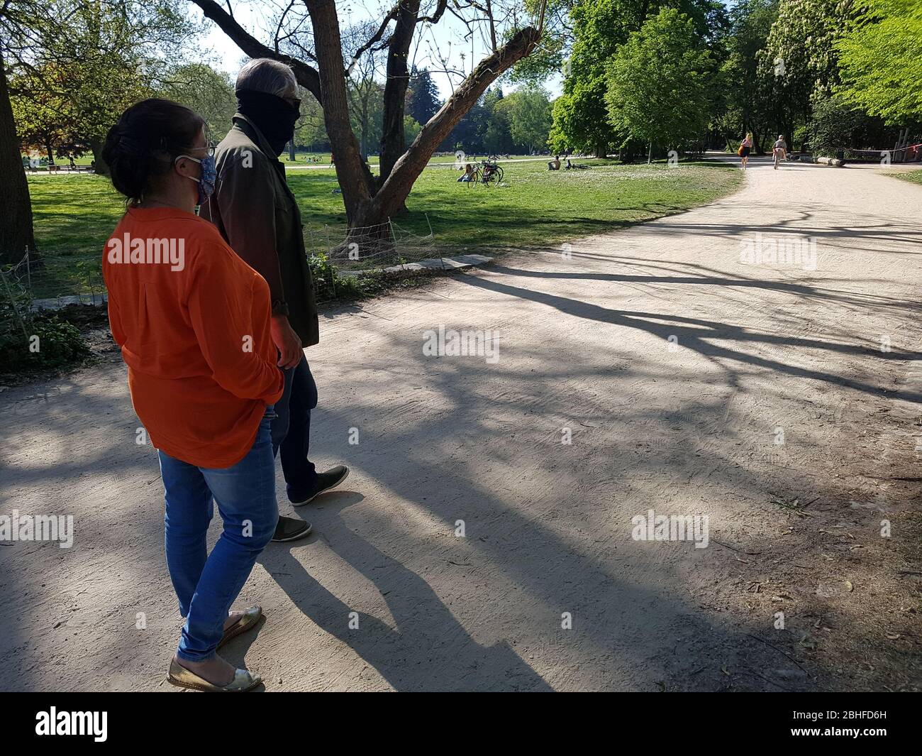 Vecchia coppia / nonni ( uomo / maschio & donna / femmina ) che indossano maschera facciale ( maschera chirurgica ), camminando attraverso il parco - covid -19 corona virus blocco Foto Stock