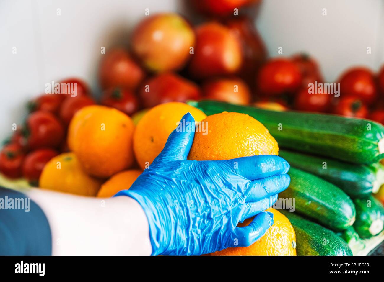 Pulito e disinfettato frutta e verdure sulla parte superiore della cucina marmorble.Woman pulizia di frutta e verdure per prevenire coronavirus con lattice blu Foto Stock