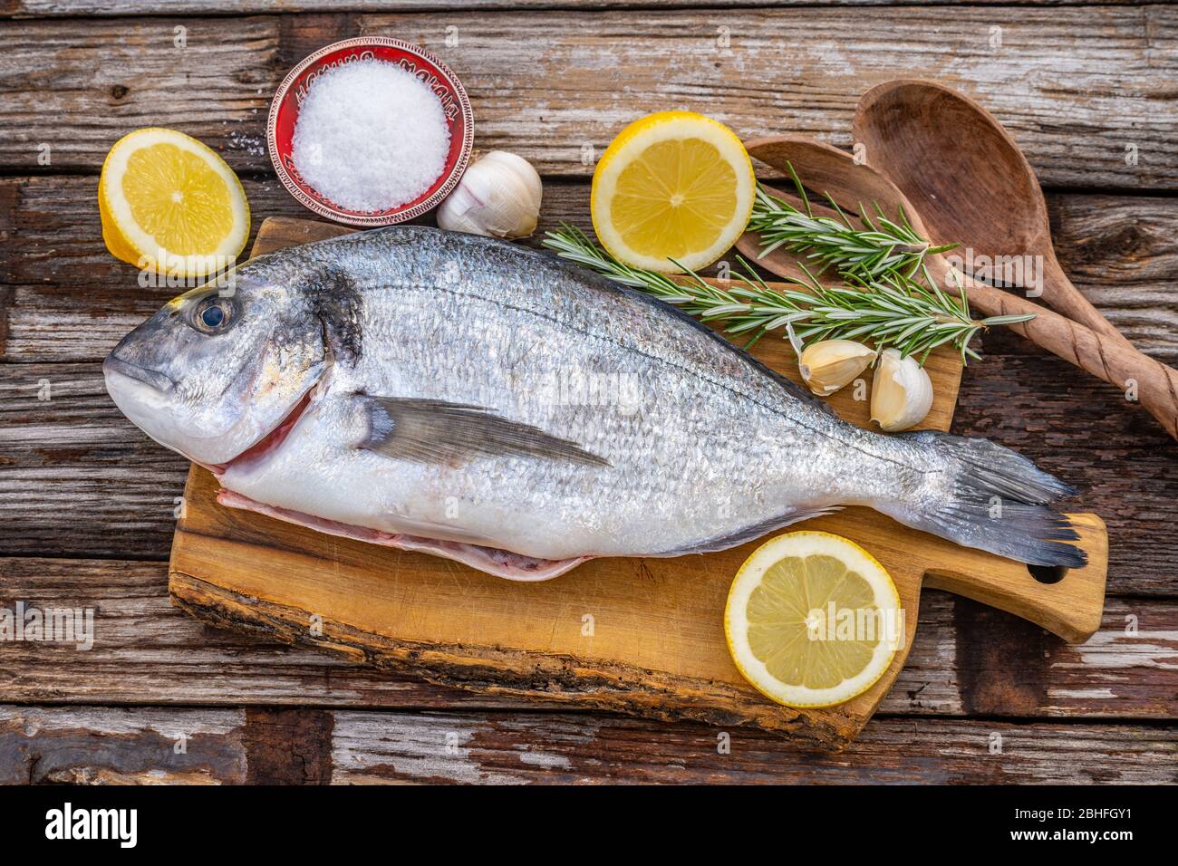 pesce di spigola fresco crudo su legno piano di cottura concetto su uno sfondo scuro in legno vista dall'alto Foto Stock