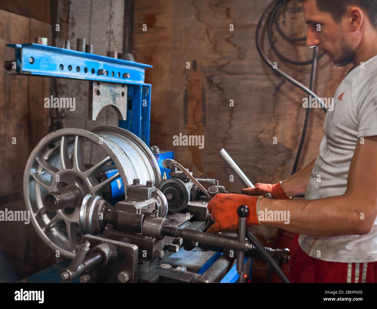 KHARKOV, UCRAINA - MARZO 2020, Service man sta ristrutturando e riparando il disco dell'automobile danneggiato in alluminio della lega alla scatola di servizio degli pneumatici. Foto Stock