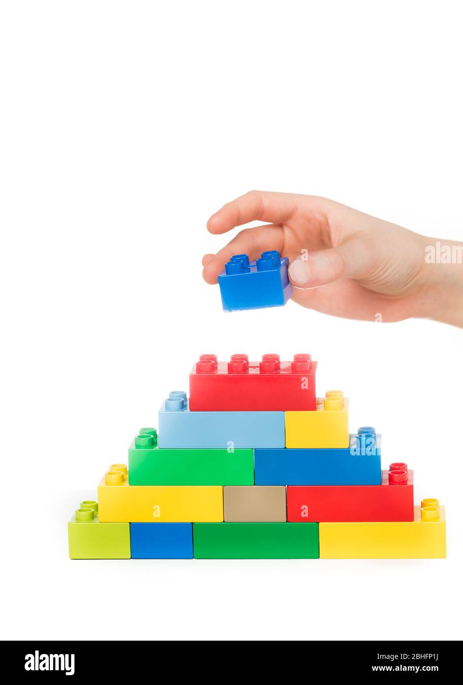 Primo piano di blocchi da costruzione per giocattoli impilabili a mano di un bambino, isolati su uno sfondo bianco Foto Stock