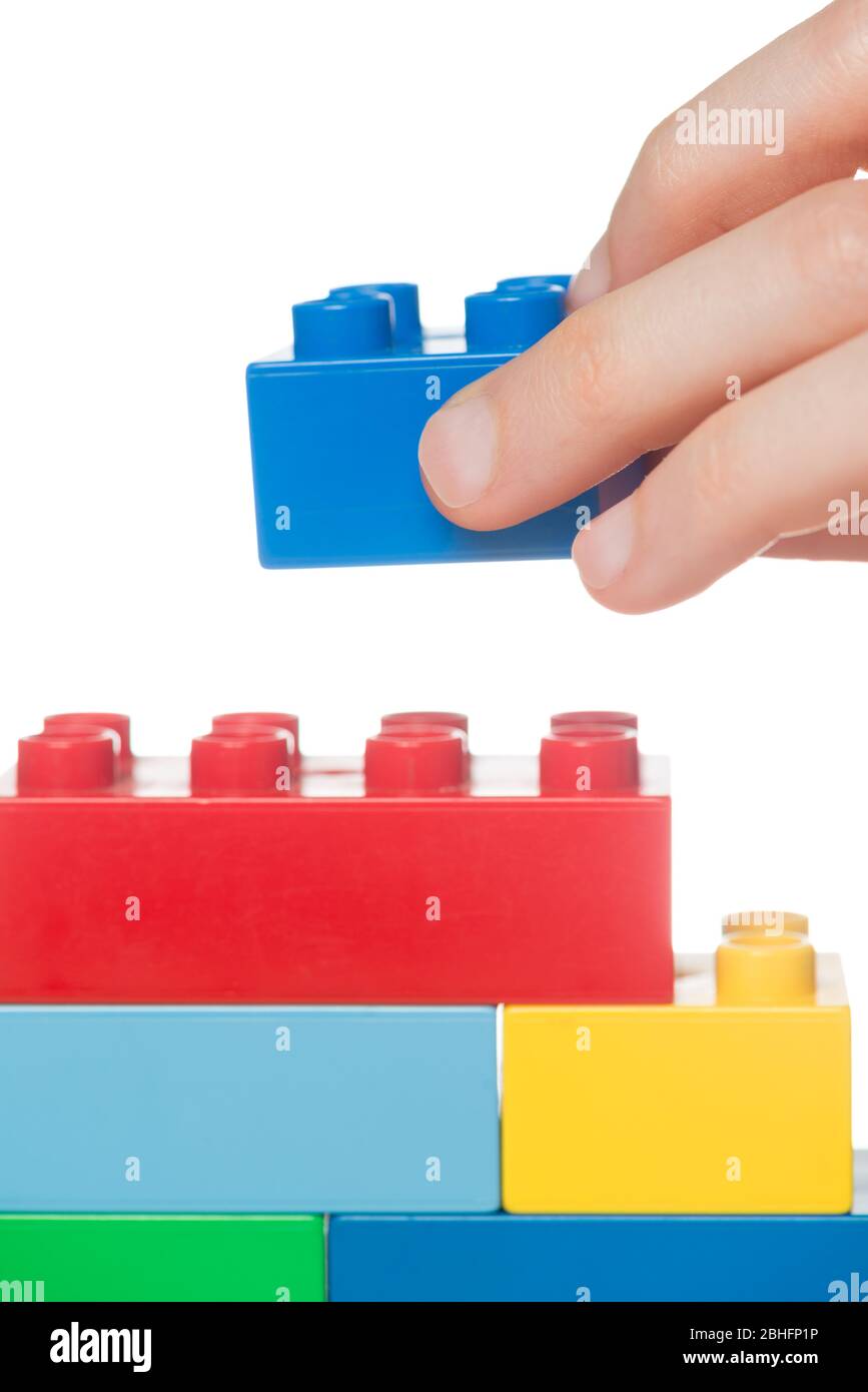 Primo piano di blocchi da costruzione per giocattoli impilabili a mano di un bambino, isolati su uno sfondo bianco Foto Stock