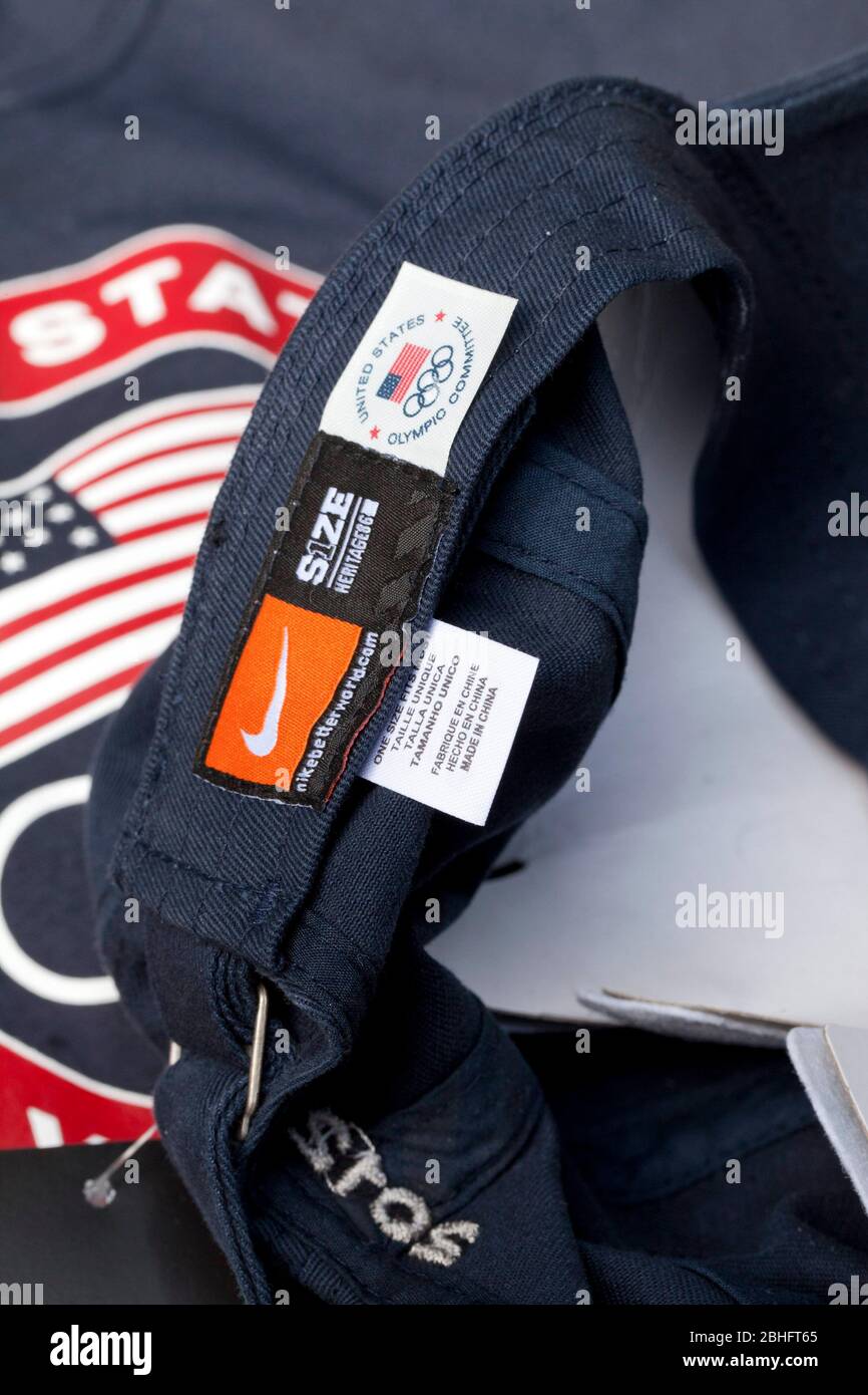 Un'etichetta "Made in China" e un'etichetta statunitense L'etichetta del Comitato Olimpico adornano un cappello della squadra olimpica degli Stati Uniti che è stato distribuito agli atleti e ai media degli Stati Uniti a Dallas nel mese di maggio. Sullo sfondo è un statunitense Maglietta della squadra olimpica con etichetta "Made in Indonesia". ©Bob Daemmrich Foto Stock