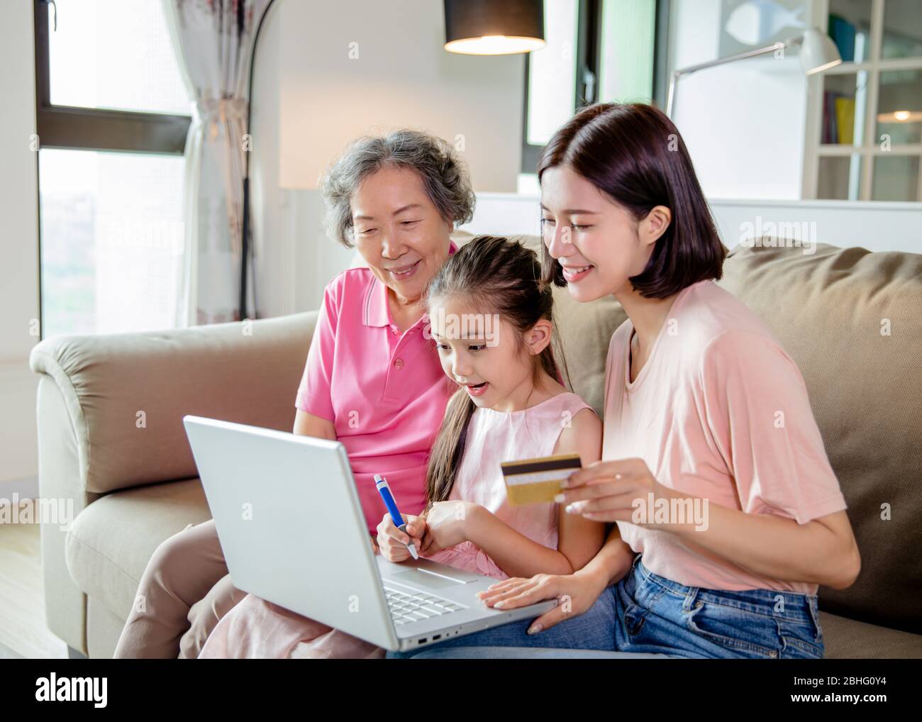 Nonna felice con bambino piccolo e figlia che ha divertimento shopping in linea a casa Foto Stock