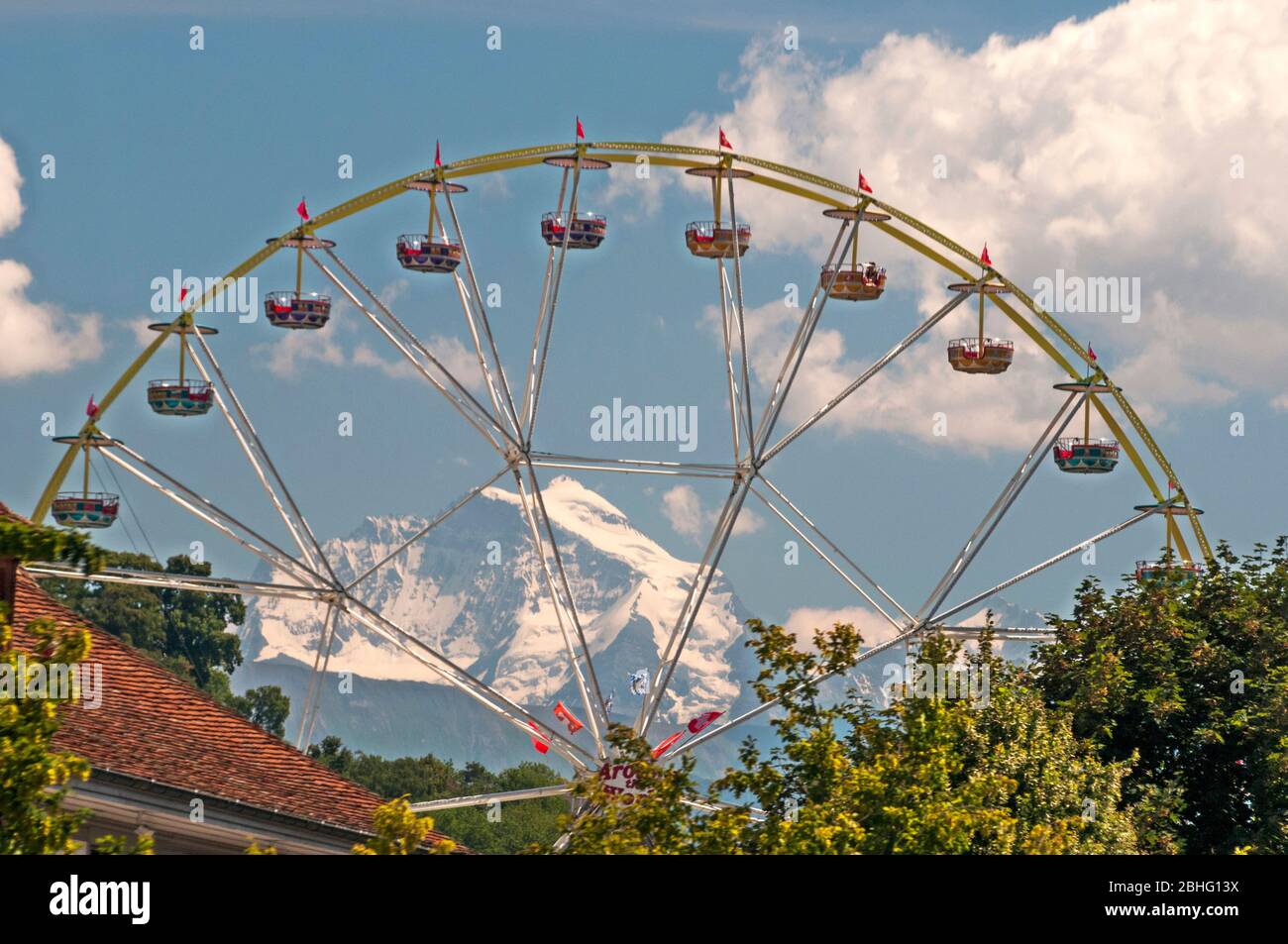 Le vette innevate della Jungfrau si innalzano oltre un parco divertimenti nella città di Thun, Canton Berna, Svizzera Foto Stock