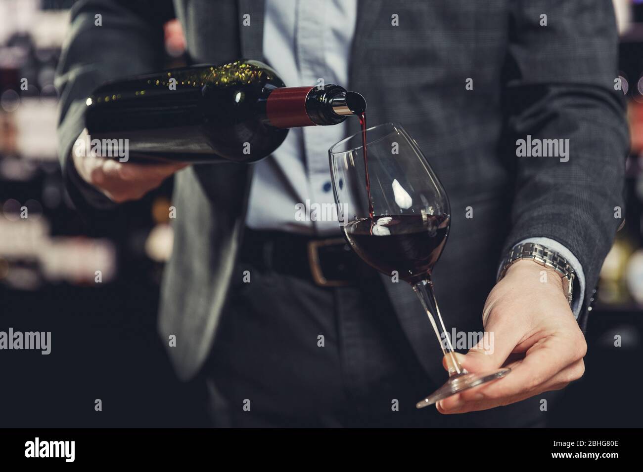 Cameriere sommelier che versa vino rosso in un bicchiere Foto Stock