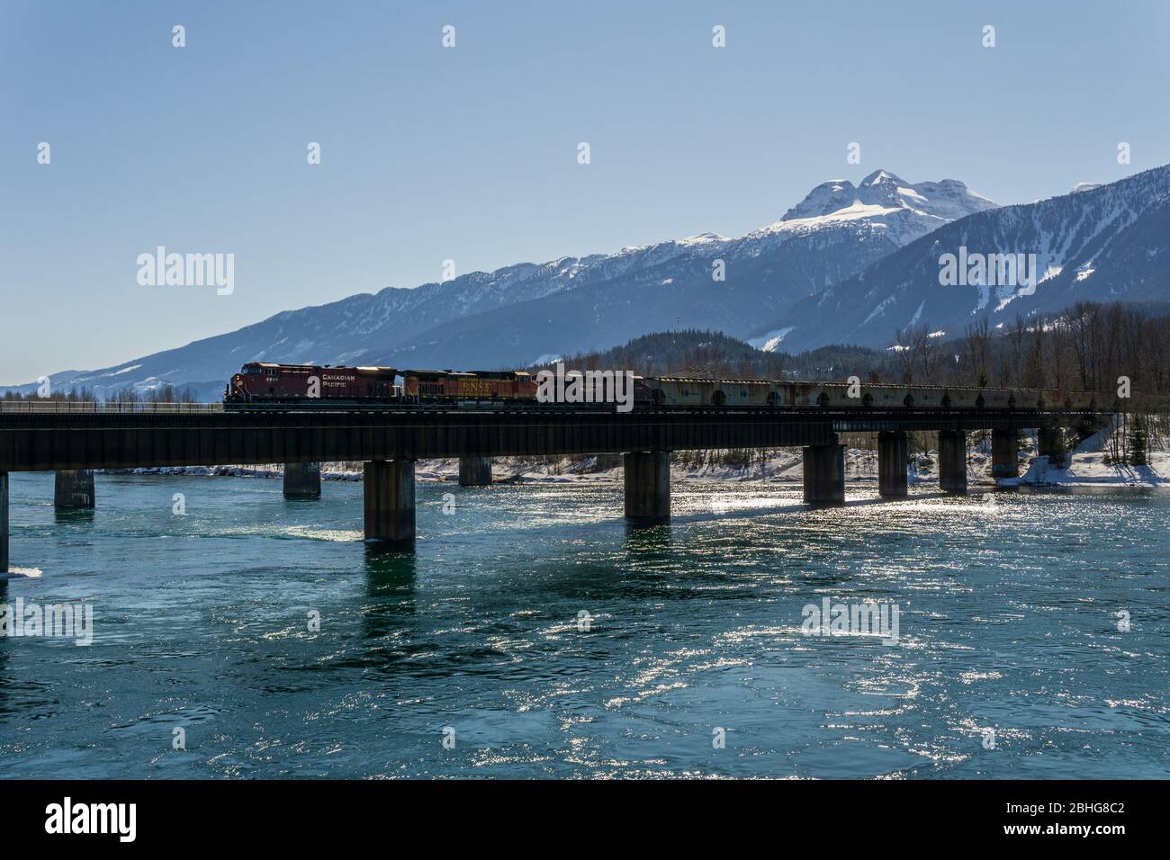 REVELSTOKE, CANADA - 15 MARZO 2020: Ponte ferroviario cargo che attraversa il fiume columbia in una giornata di primavera soleggiata. Foto Stock