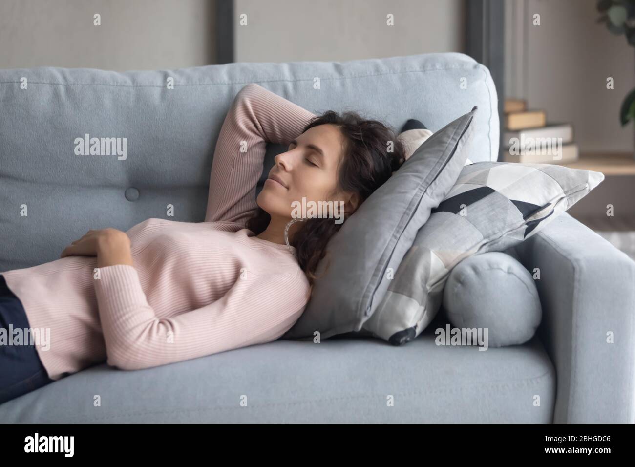 Calma piacevole ragazza millenaria che cattura daydreaming da solo sul divano. Foto Stock