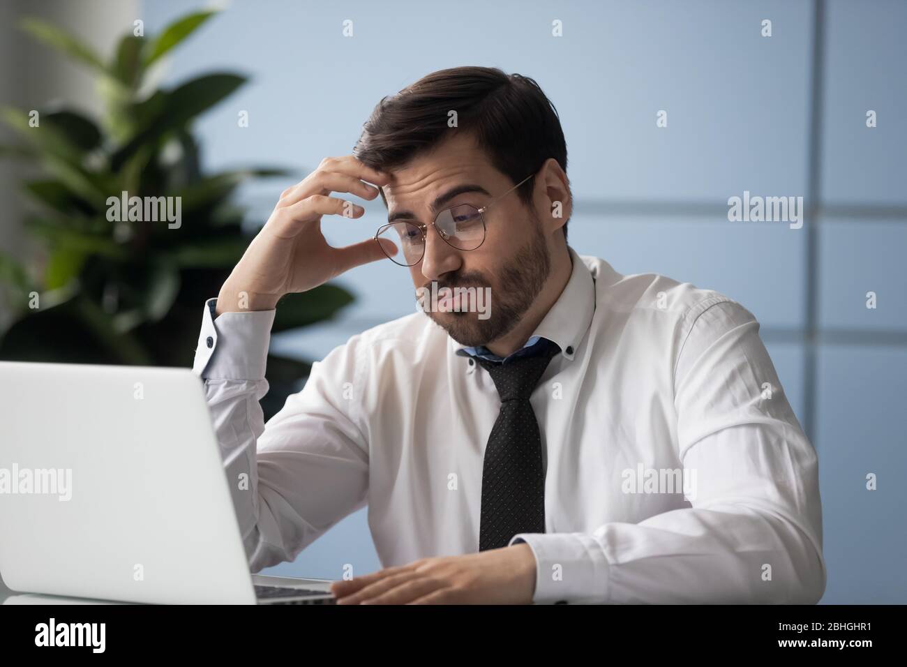 Uomo d'affari stressante che riceve cattive notizie guardando lo schermo laptop. Foto Stock